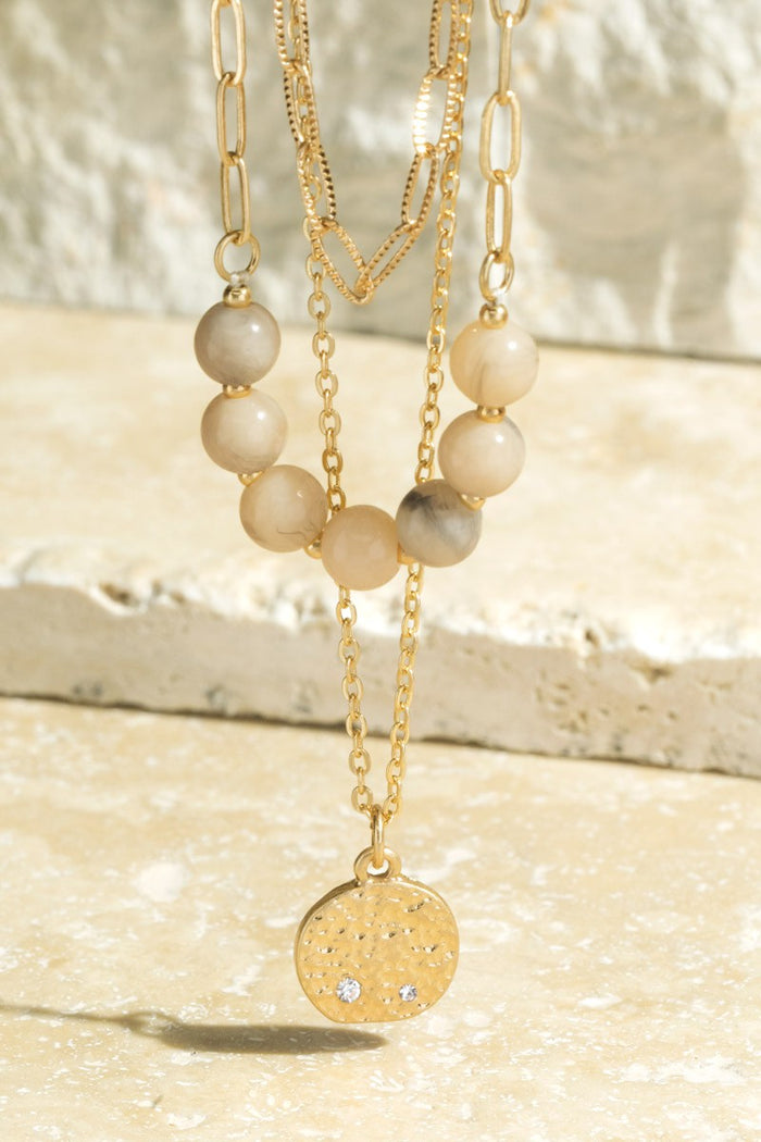 Natural stone beads and pave crystal accented disc charm on triple layered necklace
